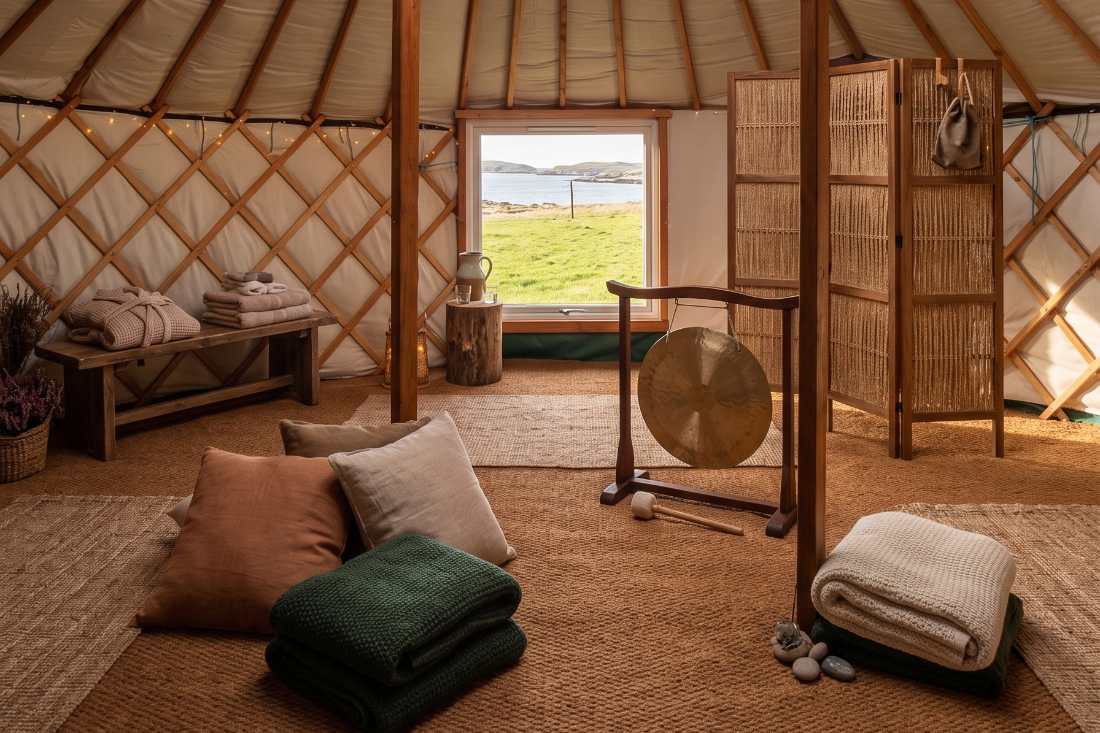 Inside the yurt: pine frame, jute floor, blankets and a window onto the sea